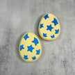 two yellow bath bombs with blue stars on a light grey background