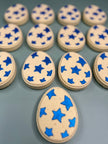 three rows of 4 yellow bath bombs with blue stars &  one single yellow bath bomb with blue stars on the bottom (total of 13 bath bombs pictured) on a light green background
