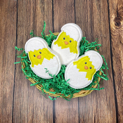 three just hatched baby chick bath bombs sitting in a easter basket with green grass on s wood picnic table background