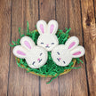 three sleeping bunny face bath bombs sitting in a easter basket on grass on a wood picnic table background